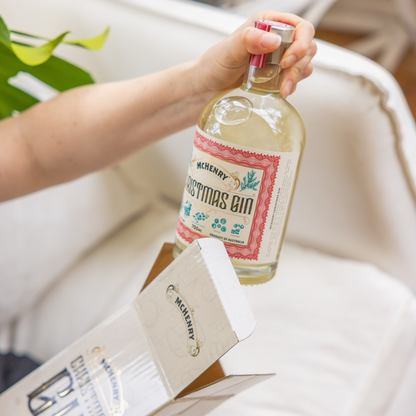 Bottle of McHenry Christmas Gin held by a hand with a blurred background