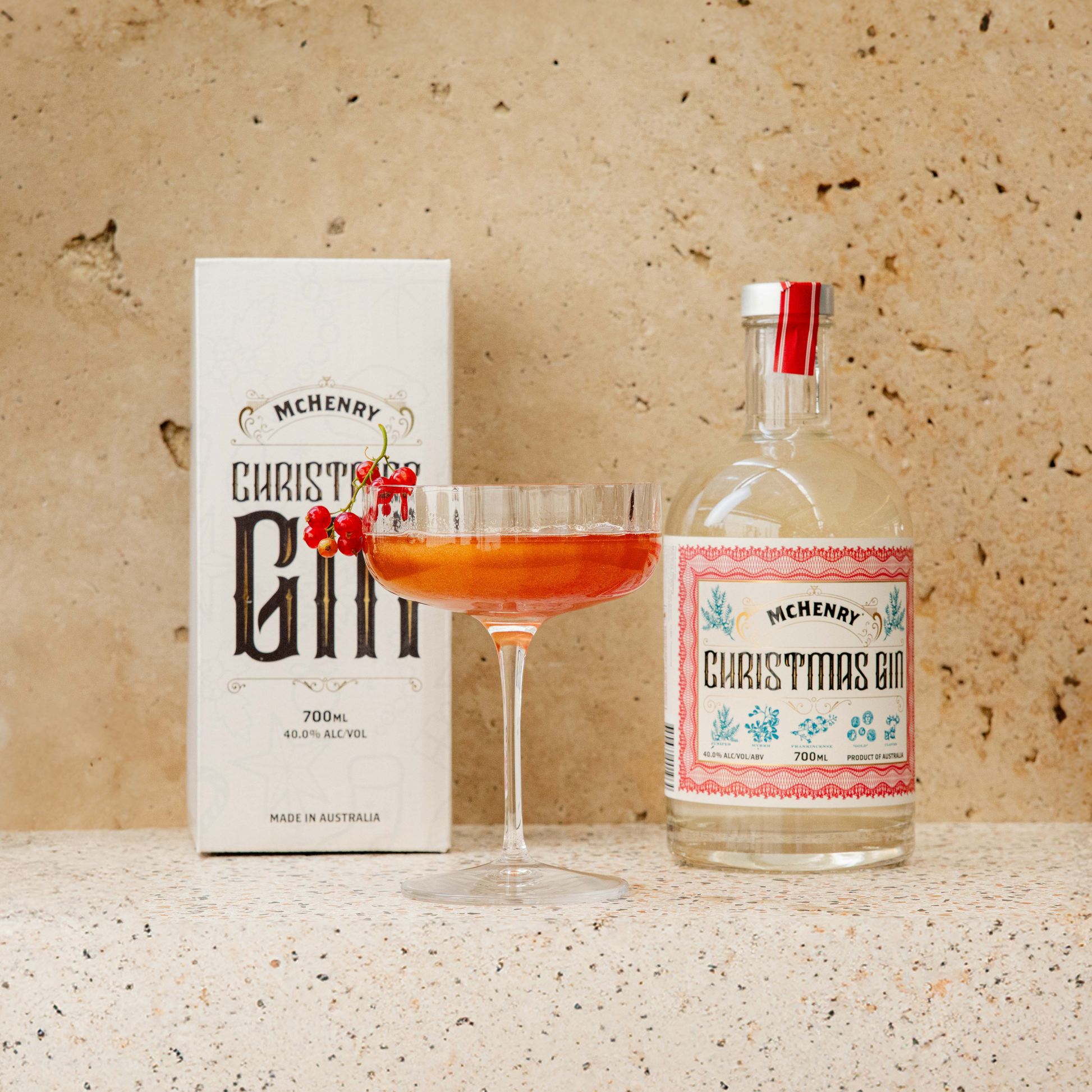 Mchenry Christmas Gin bottle, glass with cocktail, and box on a textured surface.
