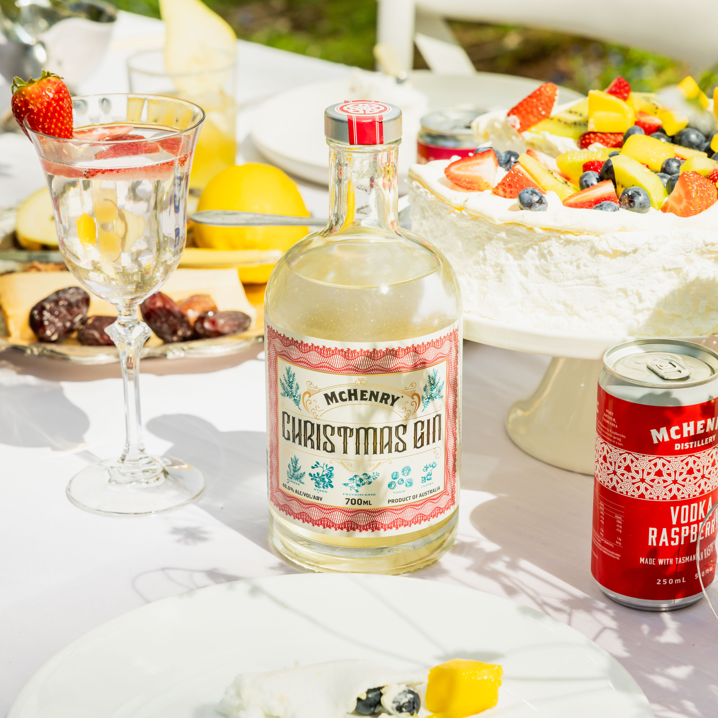 Bottle of McHenry Christmas Gin with a can of McHenry Vodka & Raspberry on a table with fruit and dessert.